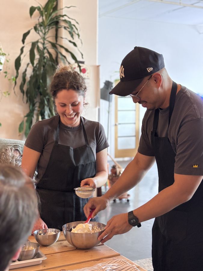 Deux collègues qui rient en préparant une crème lors d'un atelier de pâtisserie en entreprise à Montréal