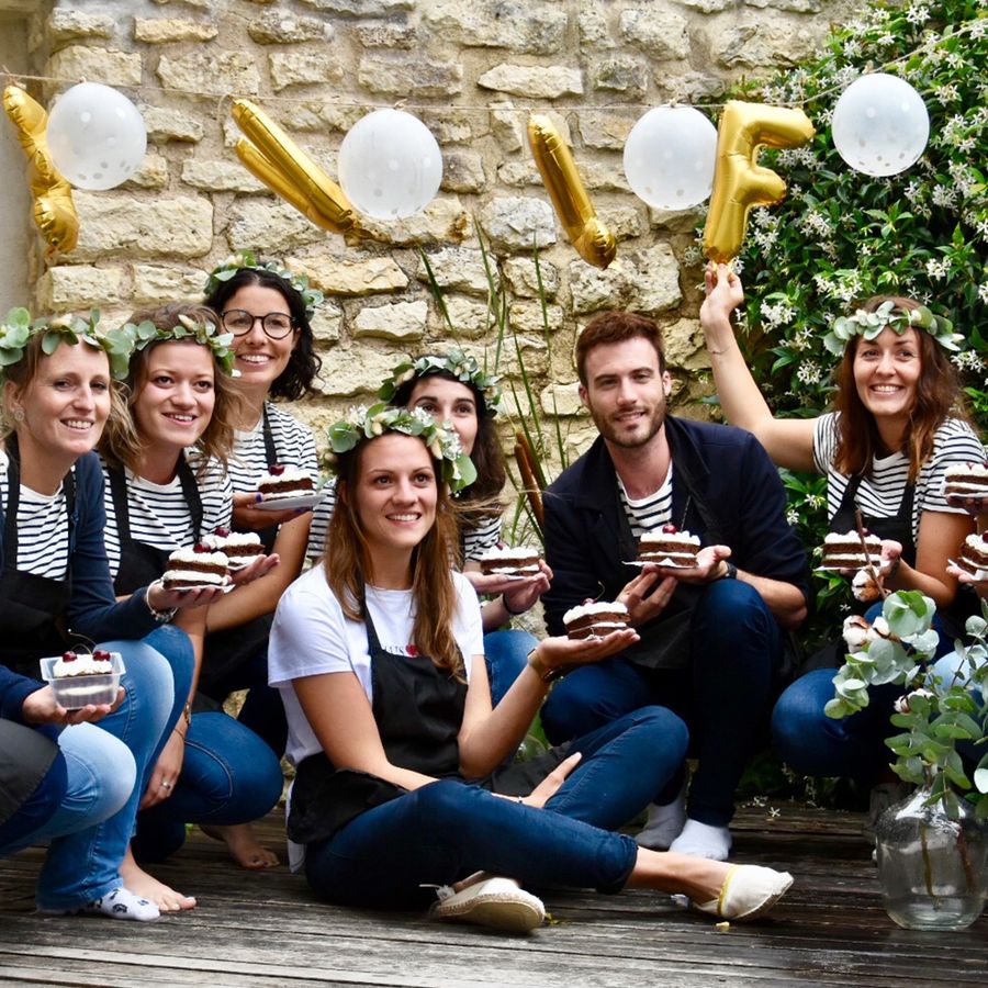Groupe d'amies souriantes avec leurs parts de gâteau lors d'un atelier de pâtisserie pour un EVJF
