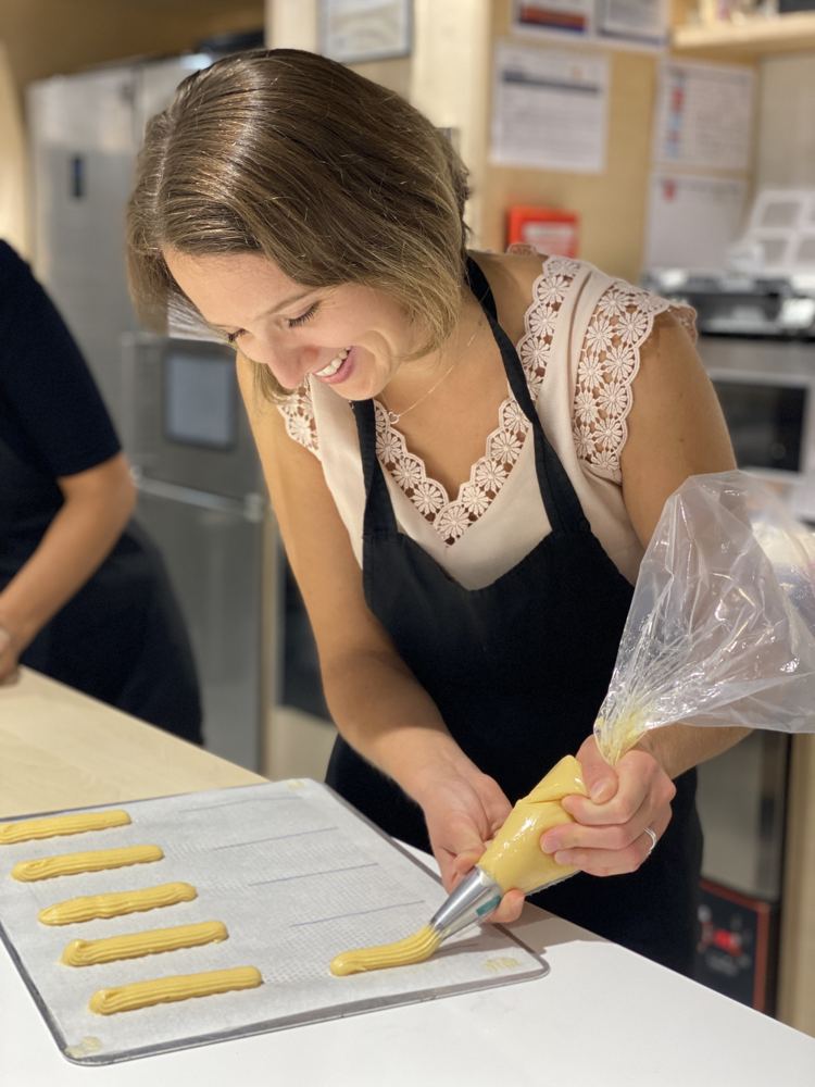 Participante souriante qui poche des éclairs pendant un atelier de pâtisserie