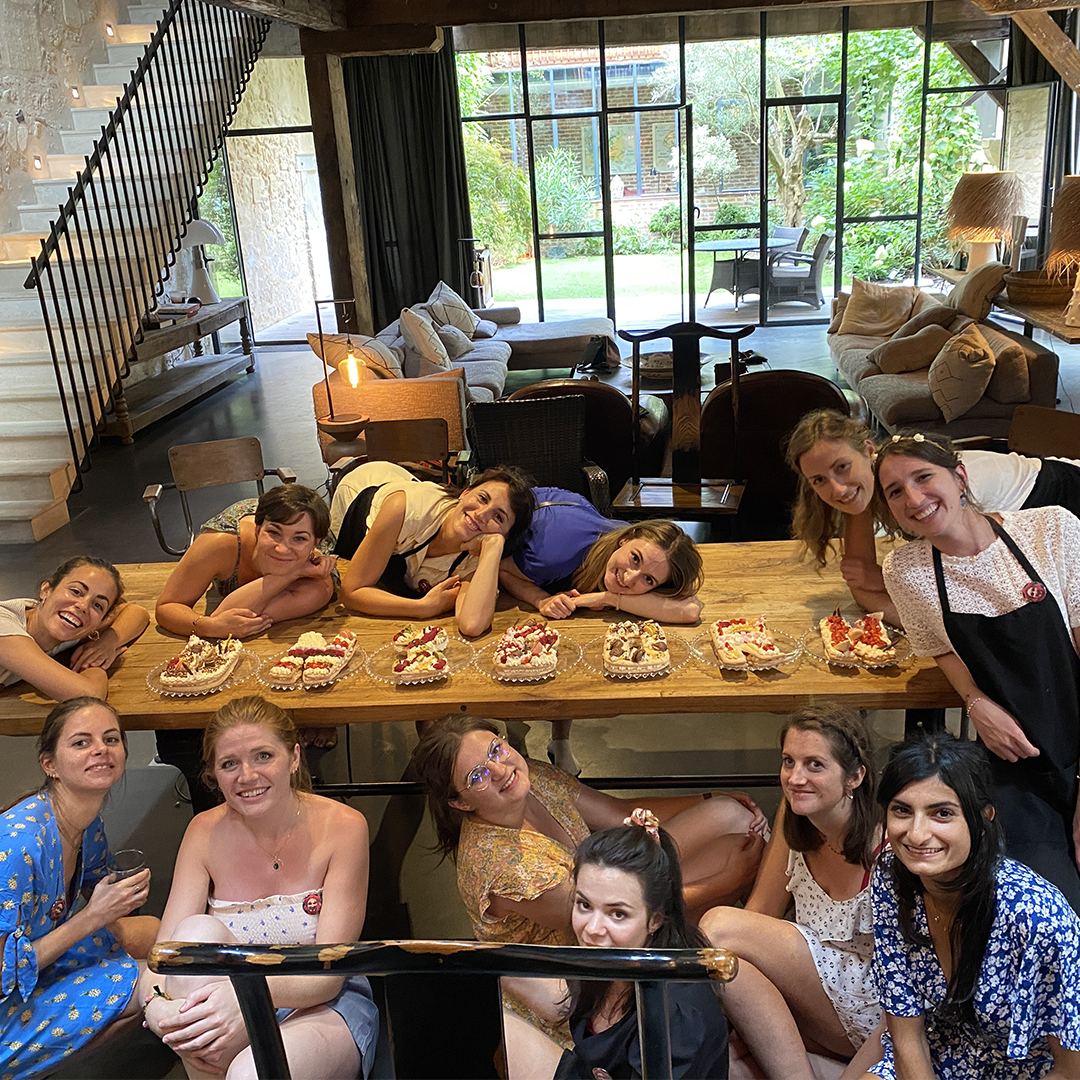 Groupe d'amies souriantes posant avec leurs letter cakes après un atelier de pâtisserie pour un EVJF