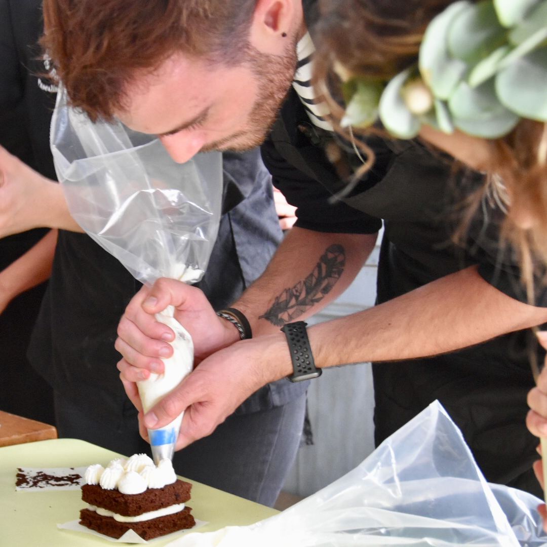 Participant qui poche la crème sur un gâteau au chocolat pendant un enterrement de vie de fille