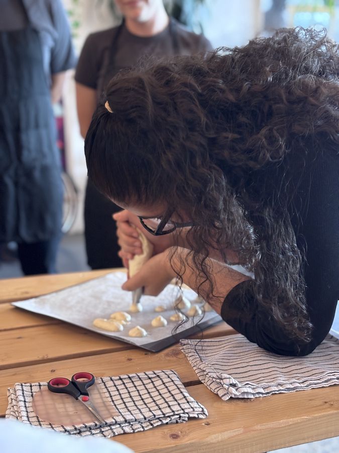 Participante qui poche de la pâte à choux pendant un atelier de pâtisserie à Montréal