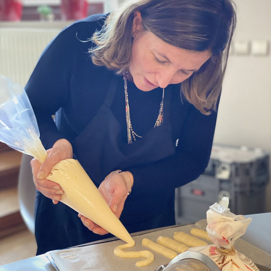 Participante qui poche de la pâte à choux pendant un atelier de pâtisserie